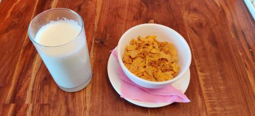 a bowl of cereal and a glass of milk on a table at Hotel Nagarkot Inn in Nagarkot