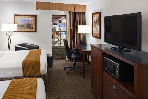 a hotel room with a bed and a desk with a television at Ramkota Hotel - Casper in Casper