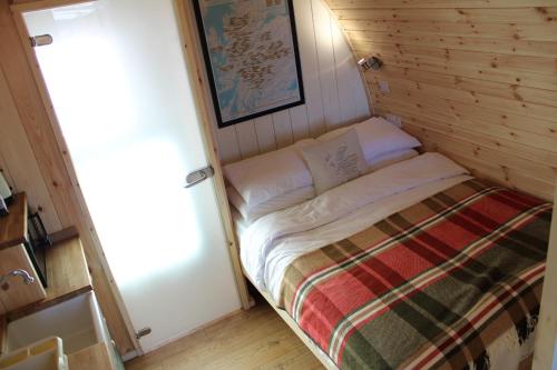 a small room with a bed in a wooden wall at Hillside Havens in Dufftown