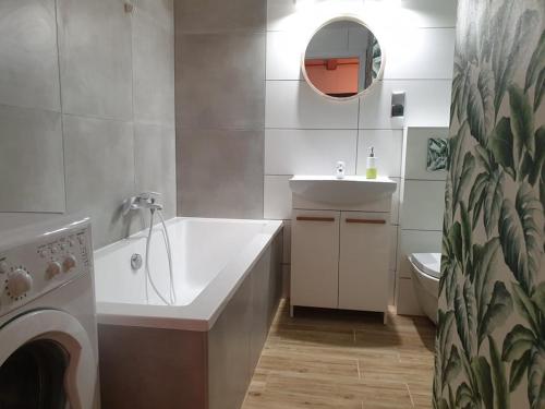 a bathroom with a tub and a sink and a washing machine at Domek z widokiem na jezioro - Domek Jerzy in Kruklanki