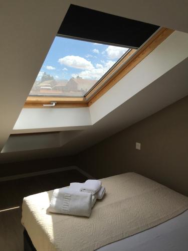 una cama en una habitación con una ventana grande en La Casa Tahona Plaza de Cervantes, en Alcalá de Henares