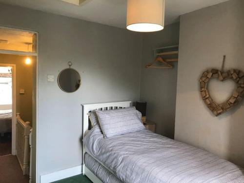 a bedroom with a bed and a heart decoration on the wall at Ham Tree Cottage in Trowbridge