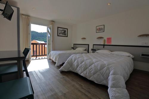a bedroom with two beds and a balcony at Hotel De l'Europe in Meyrueis