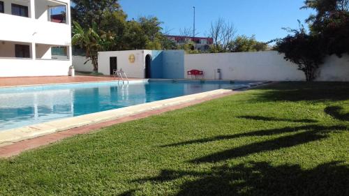 - une piscine avec de l'herbe verte à côté d'un bâtiment dans l'établissement Oura Li, à Albufeira