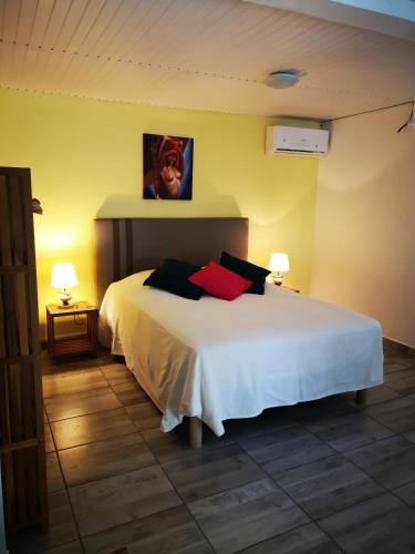 a bedroom with a white bed with two red pillows at Ti Coco in Trois-Rivières