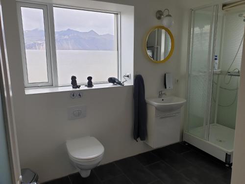 a bathroom with a toilet and a sink and a window at Hafnarnes in Höfn