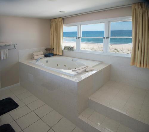 a bathroom with a tub with a view of the beach at Drifting Sands Oceanfront Hotel in Ship Bottom