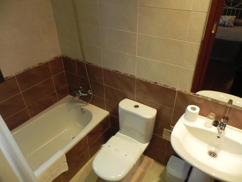 a bathroom with a toilet and a tub and a sink at Hospederia Los Pinos in Llanes