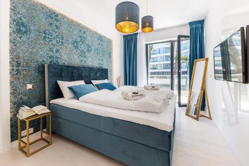 a bedroom with a large bed with a blue headboard at Dune Resort - B in Mielno