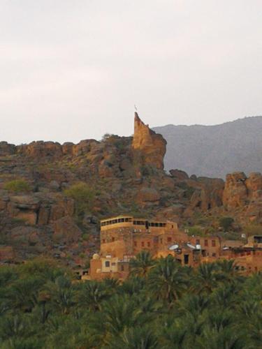 a building in front of a mountain with a rock formation at Hissen Al-Misfah in Misfāh