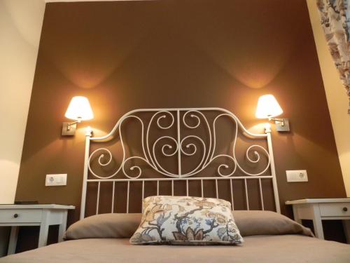 Hospederia Los Pinos في يانس: غرفة نوم مع سرير مع مصباحين على الحائط