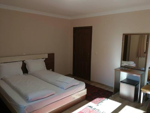 a bedroom with a bed and a desk and a mirror at Слънчевата къща in Kovachevitsa