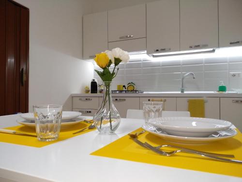 a kitchen with a table with plates and flowers in a vase at La Casa di Bianca in Caltagirone