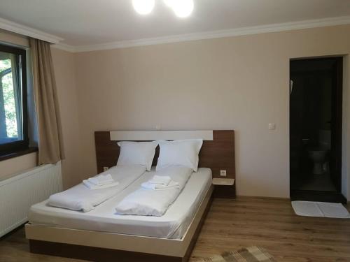 a bedroom with a bed with white sheets and pillows at Слънчевата къща in Kovachevitsa