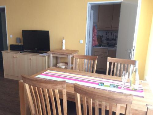 a dining room table with three chairs and a television at Ferienwohnung-Putz in Altreichenau