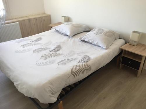a white bed with two pillows and a table at Maison de ville 3 chambres 3 salles d'eau parking 2 places in Romorantin