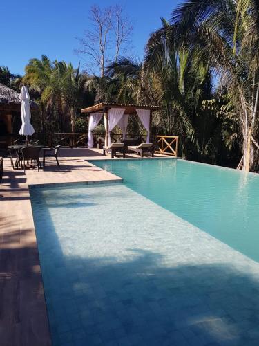 a blue swimming pool with a table and chairs at Pousada Aldeia da Serra in Palmas