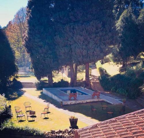 a swimming pool in a yard with chairs and trees at Terrazza Hotel in Campos do Jordão