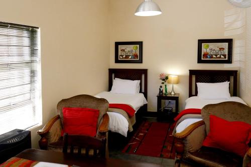 a hotel room with two beds and two lamps at A Little Guesthouse in Bloemfontein