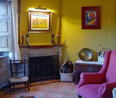 a living room with a fireplace and a pink couch at Apartamentos Rurales La Macera **** in Valencia de Alcántara