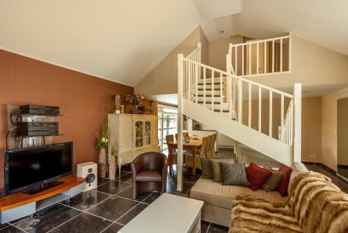 a living room with a couch and a staircase at Hof Leskensdaele Deluxe in Geraardsbergen