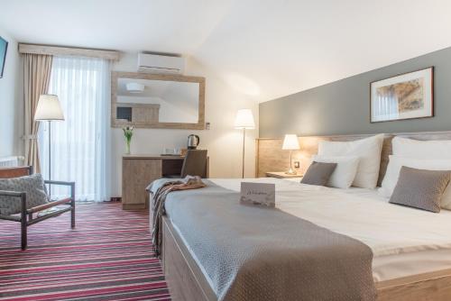 a hotel room with a large bed and a chair at GuestHouse Jagic in Plitvička Jezera