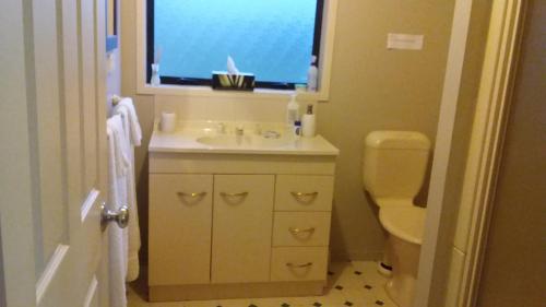 La salle de bains est pourvue d'un lavabo, de toilettes et d'une fenêtre. dans l'établissement Kaipara Views Eco Lodge, à Glorit