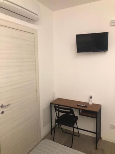 a room with a desk with a chair and a television on the wall at Ibisco Affittacamere in Iesi