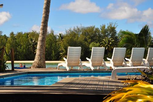 a row of white chairs next to a swimming pool at Manea on Muri in Rarotonga