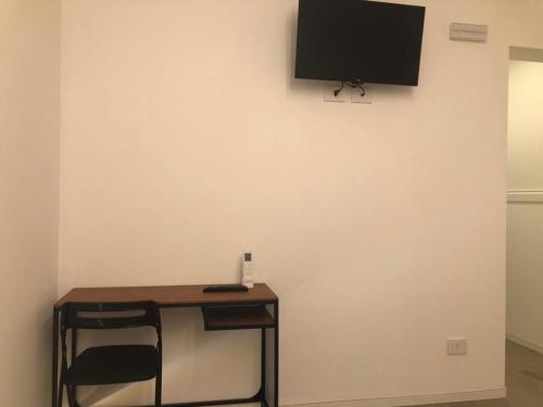 a table with a chair and a television on a wall at Ibisco Affittacamere in Iesi