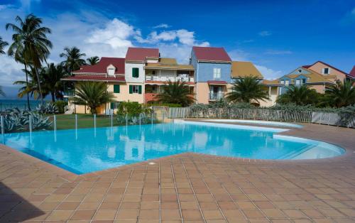 ein Swimmingpool vor einem Haus in der Unterkunft POP'S APPARTEMENTS RESIDENCE MARISOL au bord de la mer in Le Gosier
