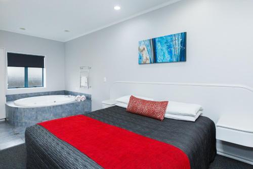 a bedroom with a bed and a bath tub at Aubyn Court Spa Motel in Palmerston North