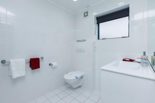 a white bathroom with a toilet and a sink at Aubyn Court Spa Motel in Palmerston North
