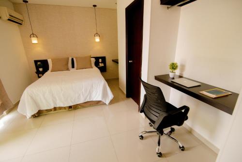 a bedroom with a bed and a desk and a chair at Hotel Maranata Valledupar in Valledupar