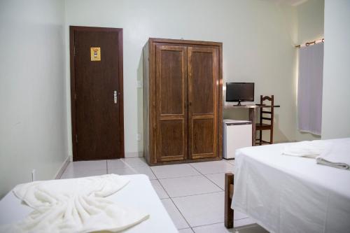 a room with two beds and a wooden door at Novo Hotel Paraopeba in Paraopeba