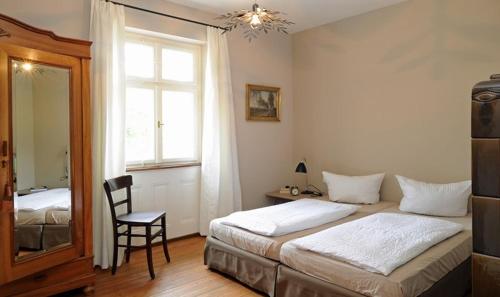 a bedroom with two beds and a chair and a window at Gasthaus Schwanen & Villa Pfarrhus in Stühlingen