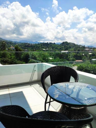 a glass table and two chairs on a balcony at Green Line in Mtsvane Kontskhi