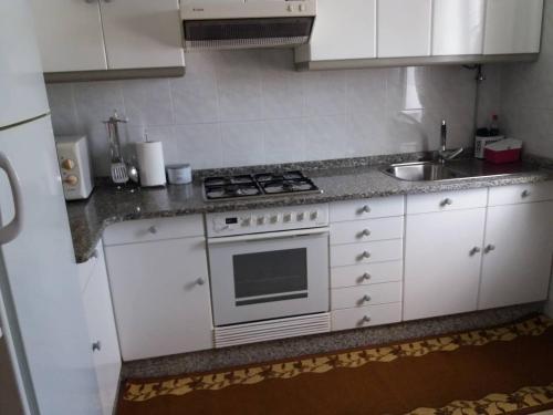 Biała kuchnia z kuchenką i zlewem w obiekcie Se alquila piso en Sanxenxo con vistas al mar w mieście Sanxenxo