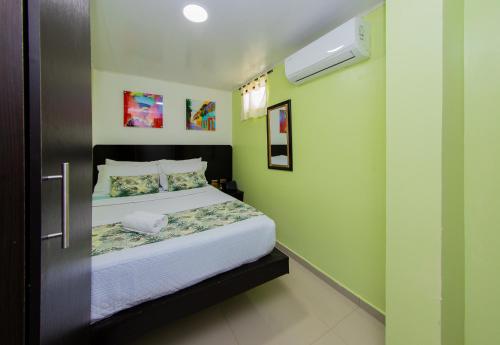 a small bedroom with a bed with green walls at Hotel Marina Suites By GEH Suites in Cartagena de Indias