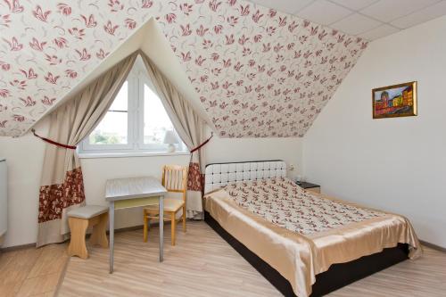 1 dormitorio con cama, mesa y ventana en Guest House Tri Klena en Velikiy Novgorod