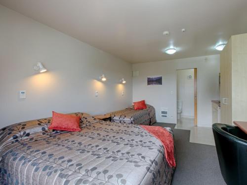 a bedroom with two beds with red pillows at Bella Vista Motel Hokitika in Hokitika