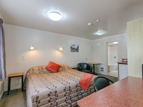 a bedroom with a bed and a table and chairs at Bella Vista Motel Hokitika in Hokitika
