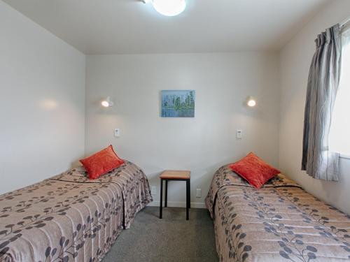 a bedroom with two beds and two lamps at Bella Vista Motel Hokitika in Hokitika