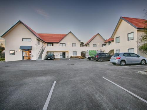 a large building with cars parked in a parking lot at Bella Vista Motel Hokitika in Hokitika