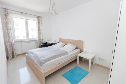 ワルシャワにあるGreen Kabaty apartment 4の白いベッドルーム(ベッド1台、青いラグ付)