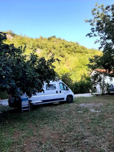 a white van parked under a tree next to a house at Auto camp Radoman in Virpazar