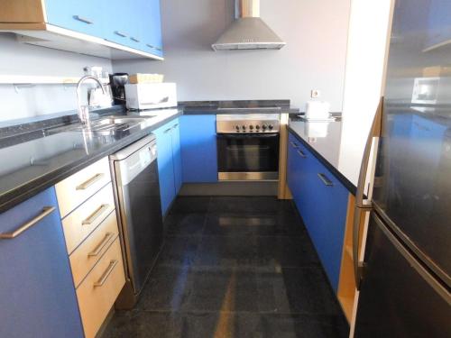 a kitchen with blue cabinets and a stove top oven at Marfolin 11 Beach Front apartment with sea views from every room in Cotillo