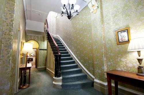 a hallway with a staircase with green wallpaper at The Nunnery Accommodation in Melbourne