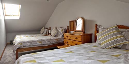 a bedroom with two beds and a dresser and a mirror at Aunt Rachel's Cottage in Bushmills