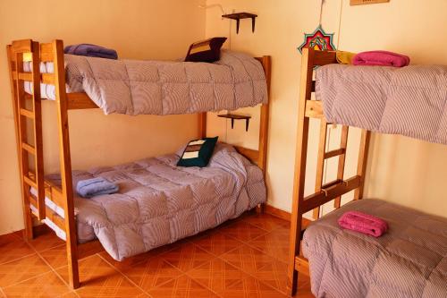a room with three bunk beds in a room at Hostal Campo Base in San Pedro de Atacama